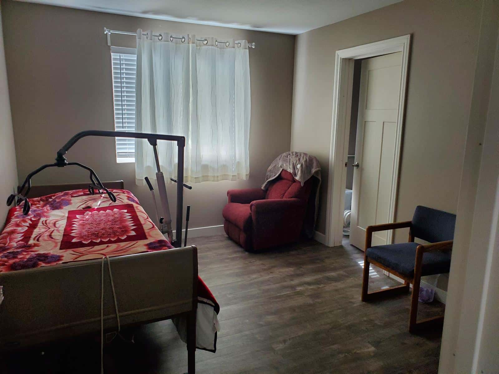 Furnished private bedroom with a made bed, lamp, and storage — ready for a new resident