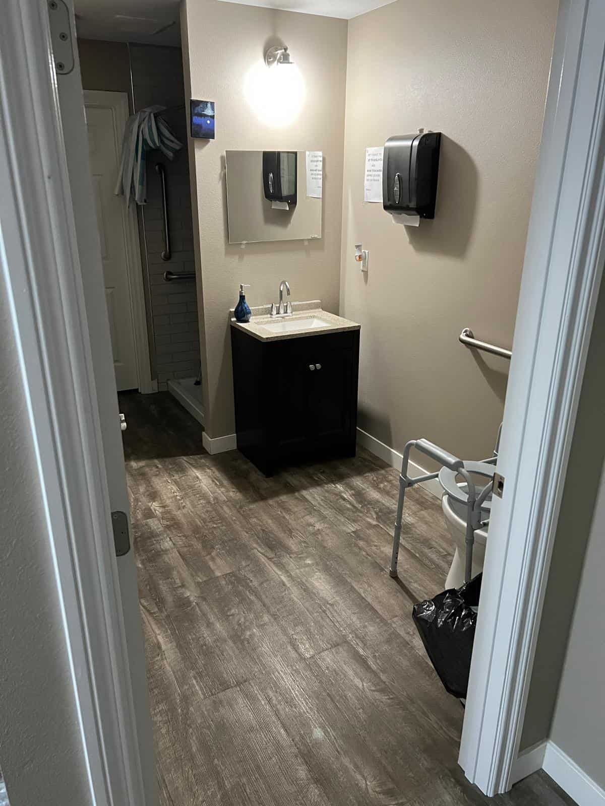 Accessible bathroom featuring handrails, non-slip flooring, and a walk-in shower for resident safety