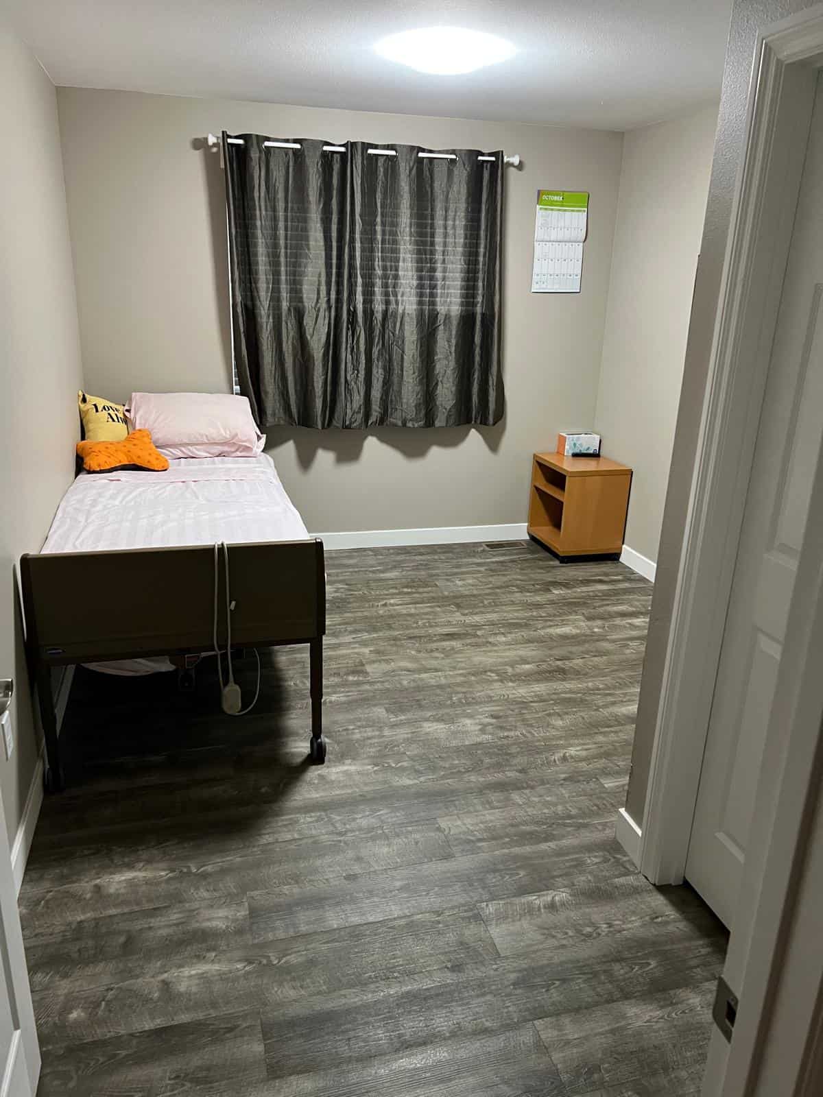 Private resident bedroom at 1st Blessed AFH with warm bedding, natural light, and personal space